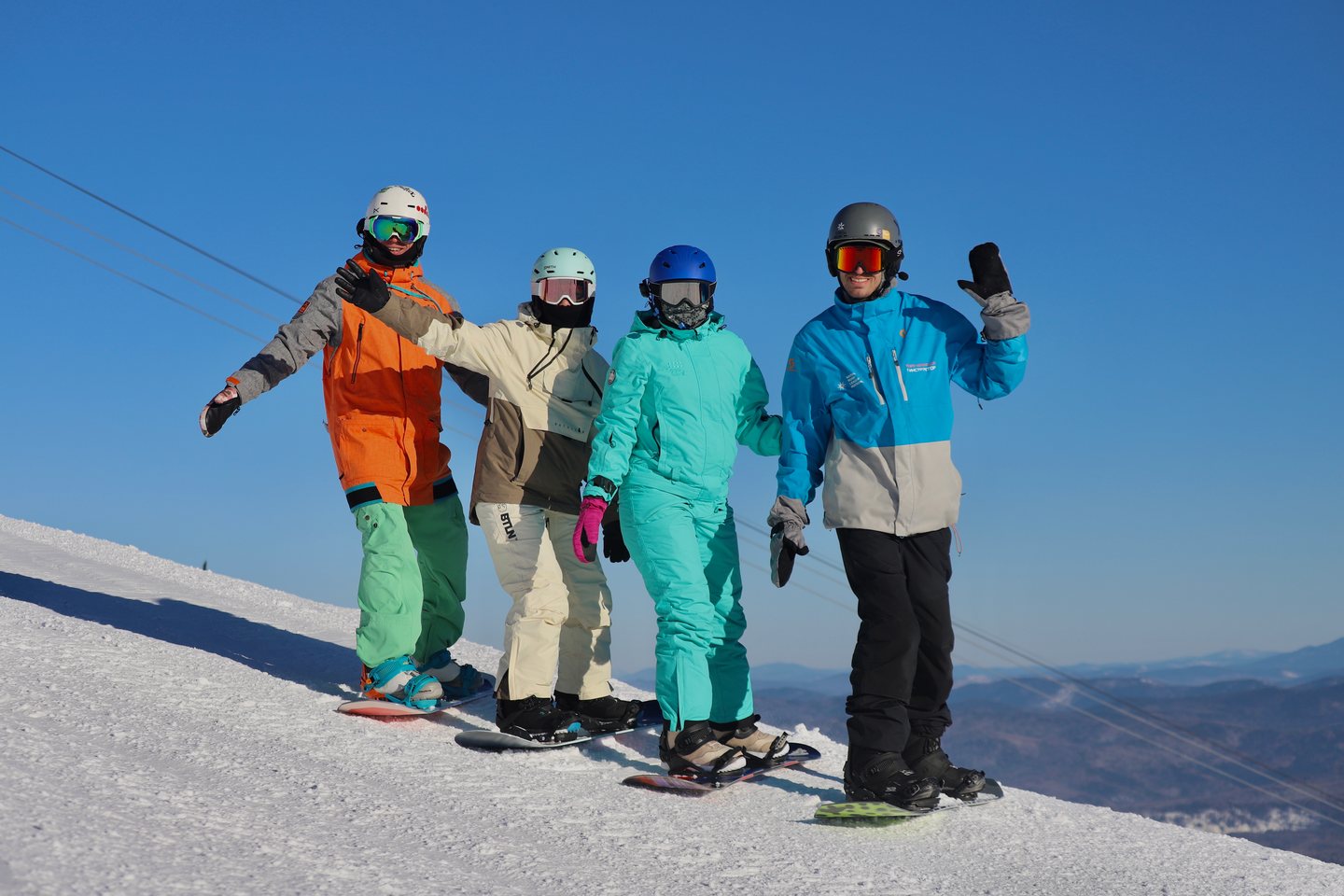Гости ГЕШ КЭМП со сноубордами на вершине склона Сектора Е в солнечный день
